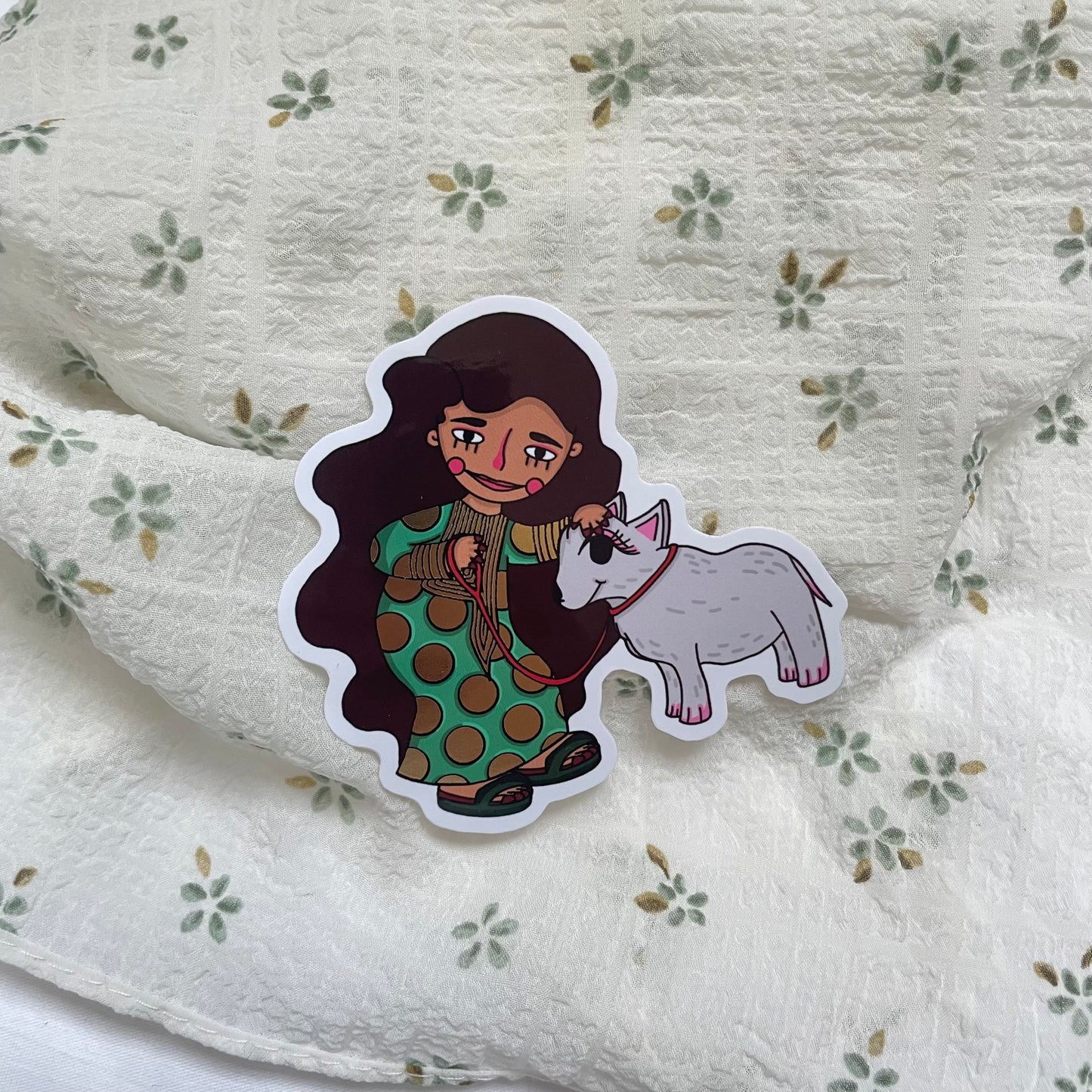 Waterproof sticker featuring an Emirati girl in traditional Mukhwar clothing with her pet sheep, accented with stunning gold foil details. Scratch-resistant and durable, perfect for decorating laptops, water bottles, and more with a touch of cultural charm and elegance.
