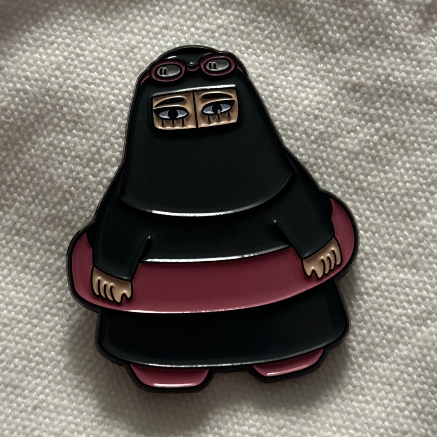 Summer Niqabi Enamel Pin featuring a niqabi woman in a cheerful summery setting. A vibrant accessory perfect for adding cultural flair and a touch of summer fun to jackets, bags, or hats, celebrating the blend of tradition and seasonal joy.
